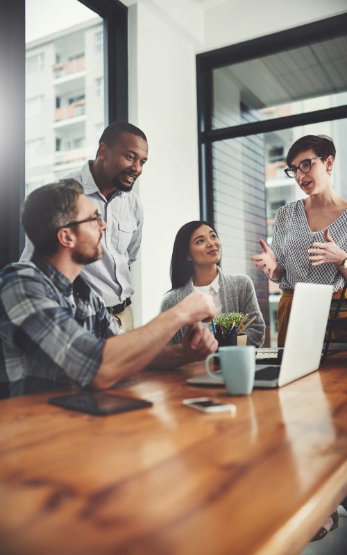 Teamwork, laptop and coaching with business people in meeting for project management, review or planning. Technology, website and training with group of employees in office for collaboration and idea.